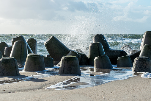 Waves hitting the breakwater concrete tetrapods on the beach