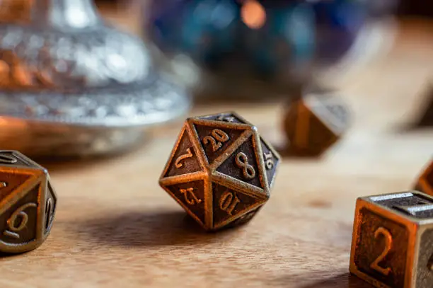 Close-up image of a metal 20-sided role-playing gaming die on a wooden surface