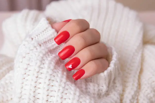 Photo of Female hand with red manicure nails, hearts design