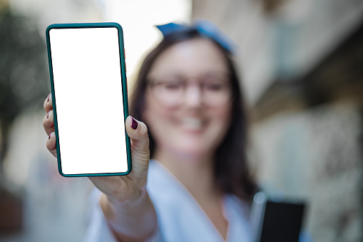 Photo of a young woman holding a smartphone with a blank screen