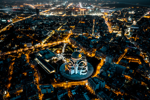 Drone point of view of residential district in Belgrade, Serbia with the Church of Saint Sava rising high above all buildings illuminated during the night.