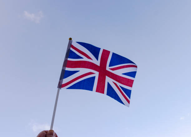 Waving the Union Jack for Platinum Jubilee Celebrations Hand holding a hand held Union Jack flag and waving it, blue sky background for Jubilee celebrations ve day celebrations uk stock pictures, royalty-free photos & images