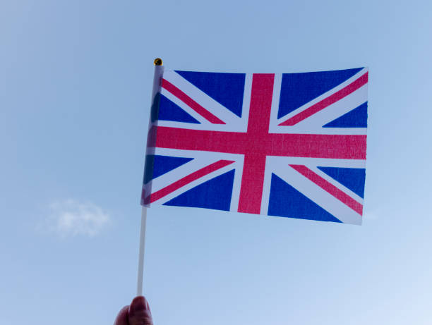 Waving the Union Jack for Platinum Jubilee Celebrations Hand holding a hand held Union Jack flag and waving it, blue sky background for Jubilee celebrations ve day celebrations uk stock pictures, royalty-free photos & images