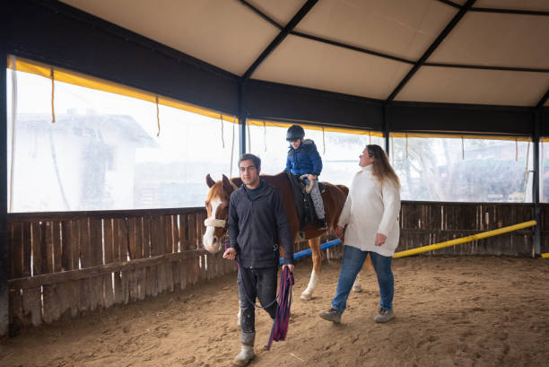 istock Woman instructor Leading a Horse with a Boy in Saddle 1367731763