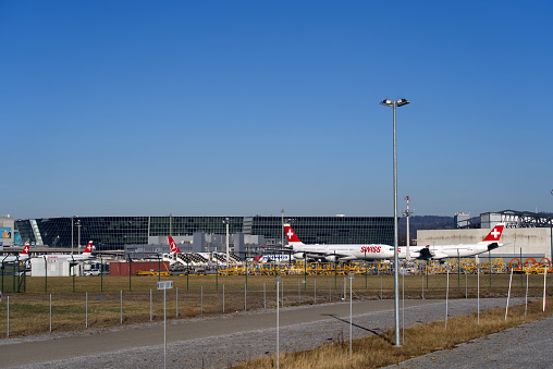 Swiss airplanes and buildings at Zürich Airport on a sunny winter day. Photo taken January 26th, 2022, Zurich, Switzerland.