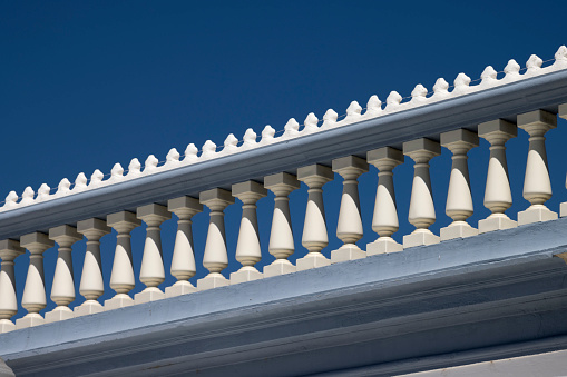 Balustrade on top of a building in Tavira, Algarve, Portugal against a deep blue summer sky.