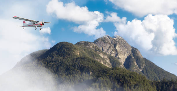 istock Airplane flying over the mountain landscape during cloudy day. 1367734576