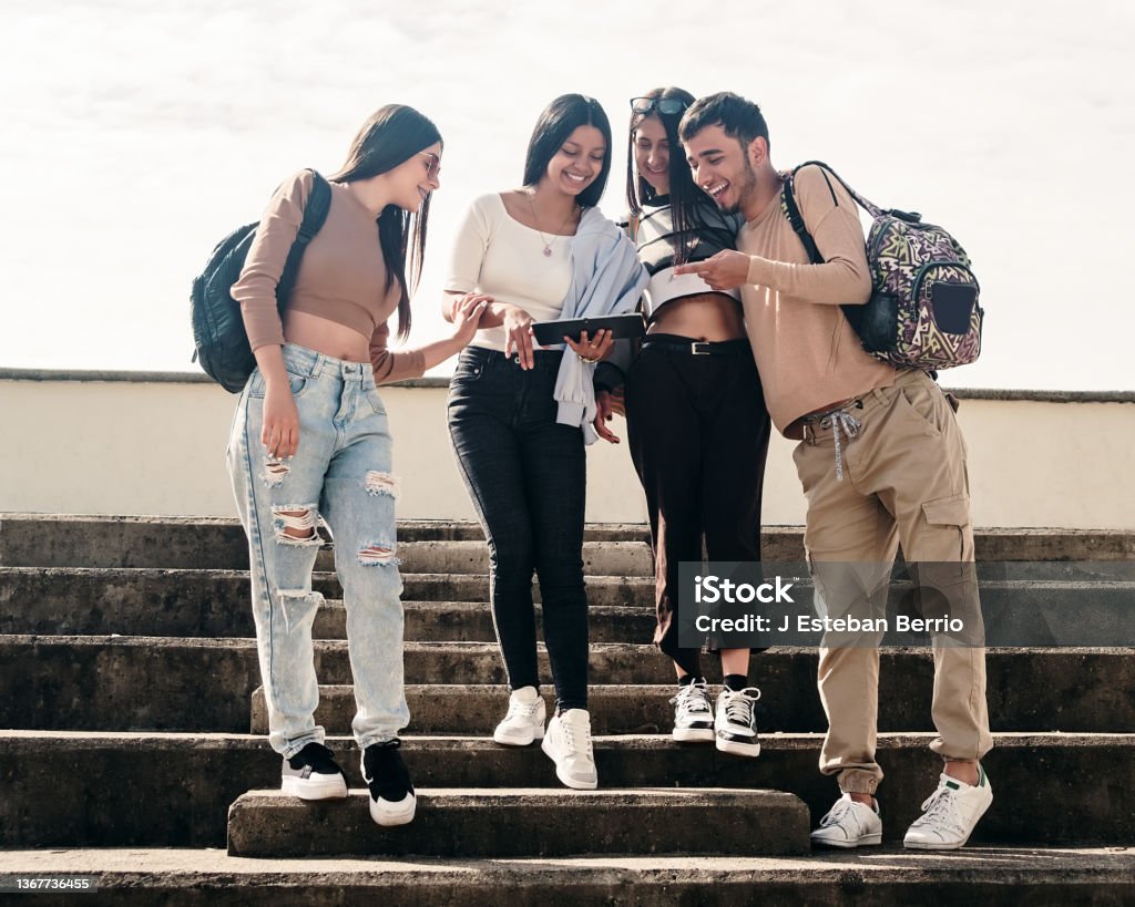 College friends smiling while looking at something on a tablet Colombia Stock Photo