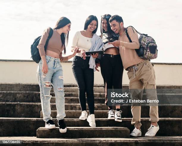 College Friends Smiling While Looking At Something On A Tablet Stock Photo - Download Image Now