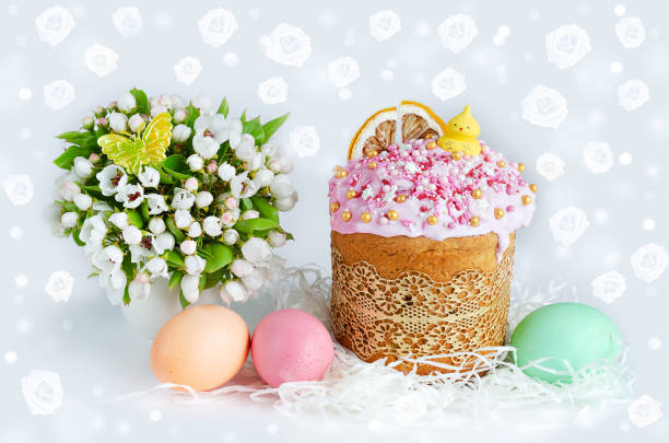 Easter cake with a chicken figurine, painted eggs and a spring bouquet. Light background with rose-shaped bokeh stock photo