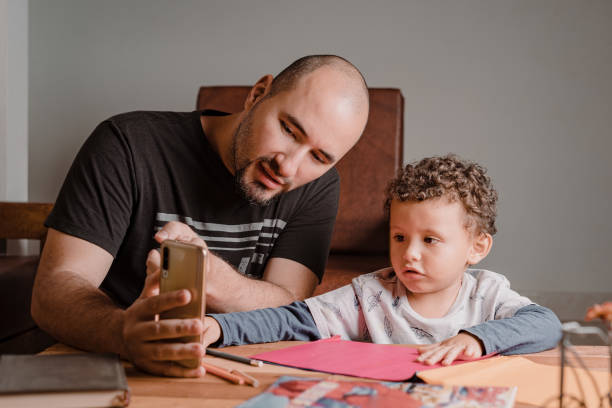 istock Dad and son watching on the cell phone drawings to do on the colored sheets 1367738587