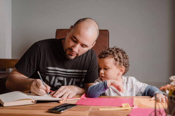 istock Dad writing in the diary while his son watches carefully what he does 1367738619
