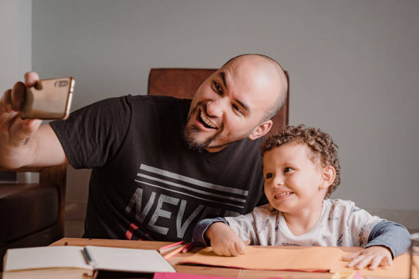 istock Dad and son making faces while taking a photo with the cell phone 1367738677