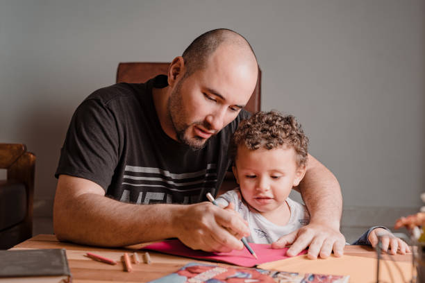istock Dad teaching his son to take the pencil to draw on the colored sheets 1367738760