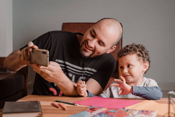 istock Son and dad looking at cell phone while enjoying homework 1367738764