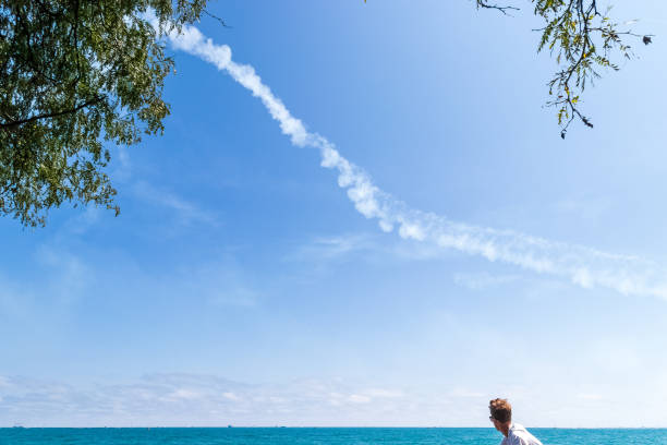 米海軍ブルーエンジェル戦闘機がミシガン湖の上空を離れる中、男は畏敬の念を持って見守る - travel destinations lake michigan freshwater standing water ストックフォトと画像
