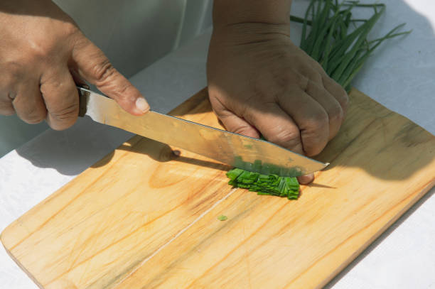 istock Woman cutting spring onion on wooden board 1367742267