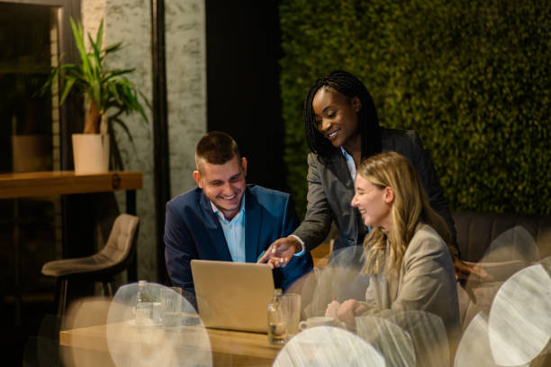 istock Cheerful work colleagues working on a laptop while having a meeting in a cafe 1367742659