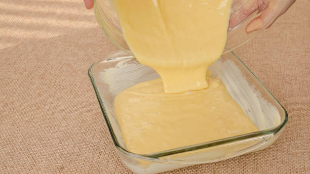 istock Biscuit dough in a glass baking dish on rustic background. Pouring batter into a dish. 1367743997