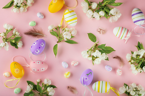 Easter eggs, blooming apple flowers on pastel pink background. Easter, spring concept. Flat lay, top view.