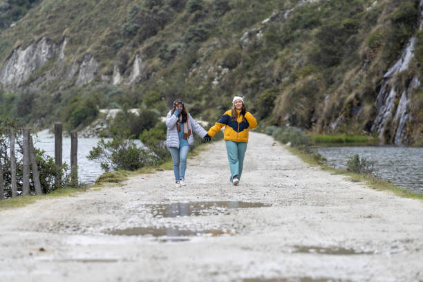 istock Lesbian couple walking while holding hands for a path next to a lake 1367744212