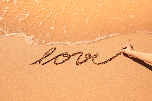 Woman drawing love sign in the sand.