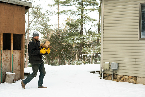 Man carrying firewood through snow to house