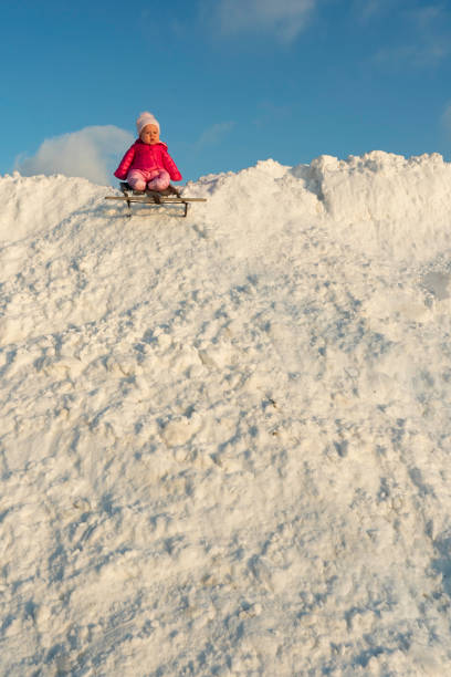 A Caucasian little girls having fun in a beautiful magic winter park during snowfall