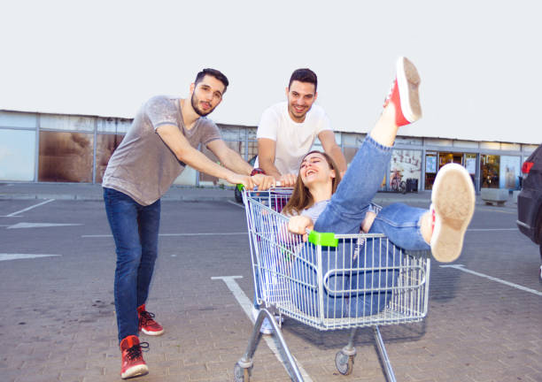 istock Three Young People Amuse On Parking Lot With Shopping Cart 1367750149