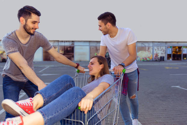 istock TWO GUYS RIDING SHOPPING CART WITH BRUNETTE SITTING INSIDE 1367750155
