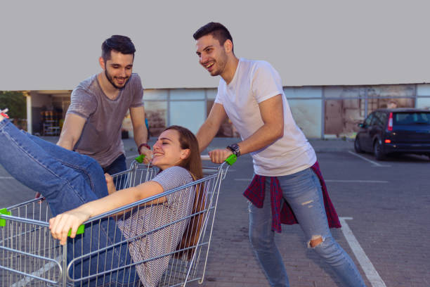 istock TWO GUYS RIDING SHOPPING CART WITH BRUNETTE SITTING INSIDE 1367750157