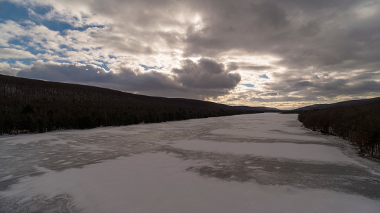 Winter evening with the dramatic cloudy sky over the Mauch Chunk Lake near Jim Thorpe, in Appalachian Mountains, Pennsylvania, Pocono Region, USA. Aerial view.