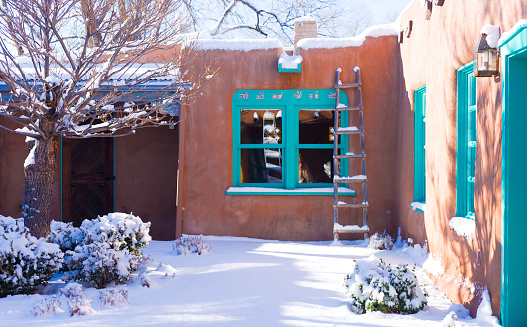 Santa Fe/Southwest Style: Old adobe home exterior in snow.