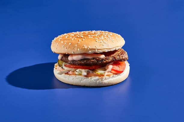 istock Beef burger blue background with hard shadow. American junk food minimal style. Hamburger trendy style.  Simple burger colour background. 1367758396