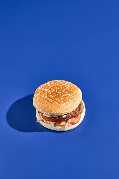 istock Beef burger blue background with hard shadow. American junk food minimal style. Hamburger trendy style.  Simple burger colour background. 1367758400