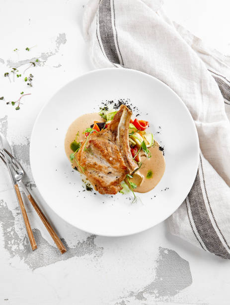 istock Roasted pork steak with vegetables garnish and sauce. Bone-in ribeye pork chops. Main course of pork in rustic style. 1367758414
