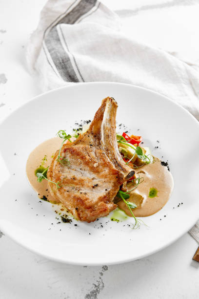 istock Roasted pork steak with vegetables garnish and sauce. Bone-in ribeye pork chops. Main course of pork in rustic style. 1367758417