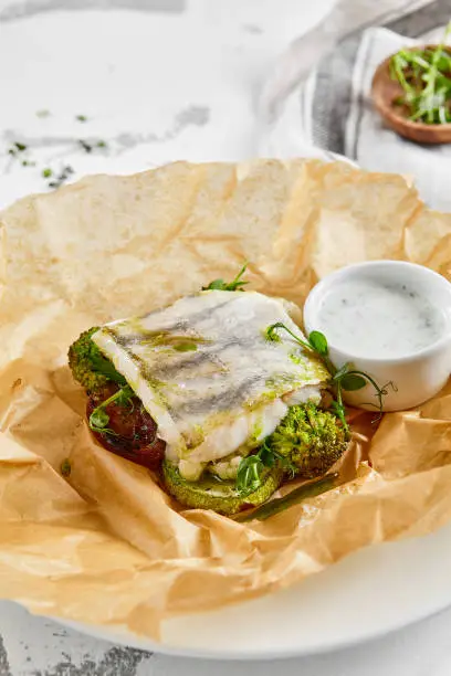 White fish fillet with broccoli in rustic style. Healthy eating: cooked fish fillet with vegetables garnish. Diet food with white fish and broccoli. Steam vegetables with roasted zander fillet