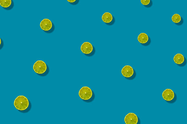 istock Colorful fruit pattern of fresh limes slices on blue background with shadows. Top view. Flat lay. Pop art design 1367760999