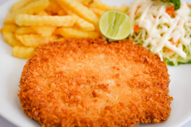 istock Pork schnitzel with fries and vegetables on white plate. 1367762636
