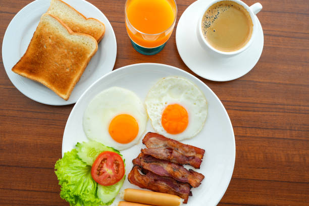 istock Top view set bacon bread hotdog fried eggs and drink on wooden table. 1367762687