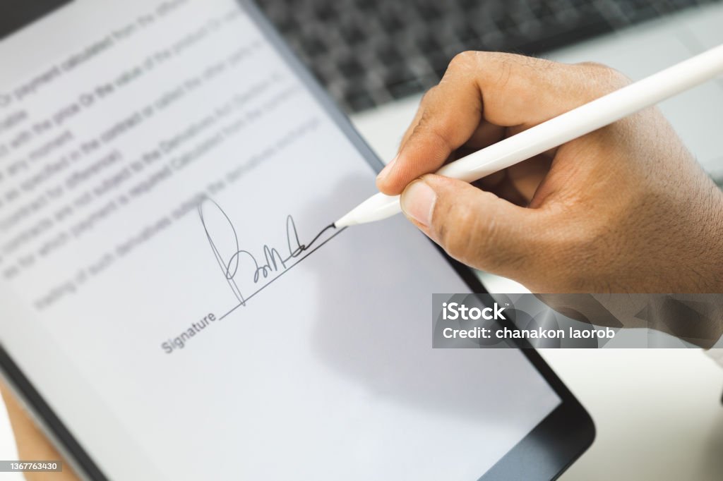 Close up businessman hand electronic Signature on Tablet by Stylus. Write business agreement of contract. Man signing contract on tablet. Business and technology concept. Signature Stock Photo