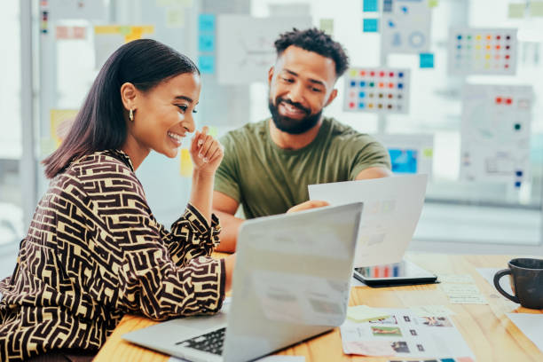 istock Shot of two young designers going through paperwork while working on a laptop together in an office 1367764247