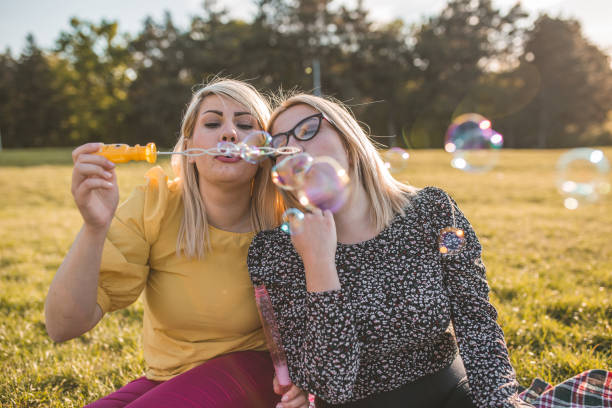 istock Sisters having fun making soap balloons in the park 1367769533