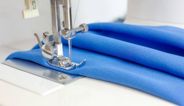Sewing machine foot with needle and blue fabric. sewing process. concept of making clothes .Empty space for text Sewing machine foot with needle and blue fabric. sewing process. concept of making clothes .Empty space for text sewing machine stock pictures, royalty-free photos & images