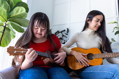 Diverse sisters playing together, one has Down’s syndrome.