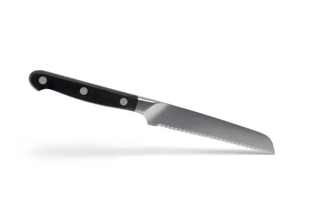 Close up of high quality small bread knife with black handle and serrated blade against white background