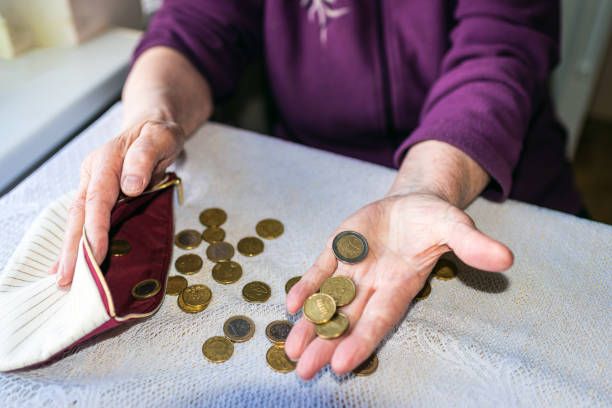 vecchia donna seduta miseramente a casa e contando le monete rimanenti della pensione nel suo portafoglio dopo aver pagato le bollette. - miseramente foto e immagini stock