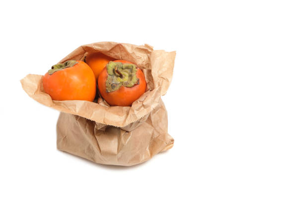 Persimmon fruit in a grocery paper bag on a white background