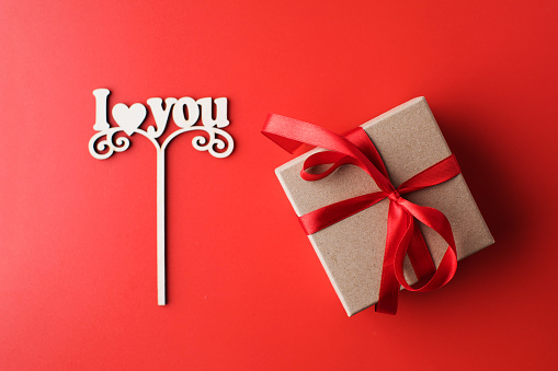 Flat lay gift box and a sign with the words I love you on a red background. The concept of Valentine's Day. High quality photo